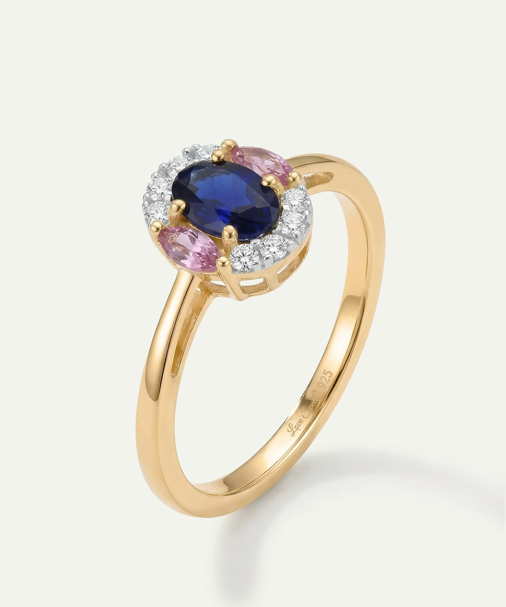 Gold ring with a blue gemstone and pink stones on a white background