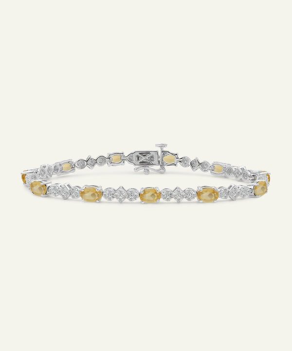 Diamond bracelet with yellow and white gemstones on a light gray background