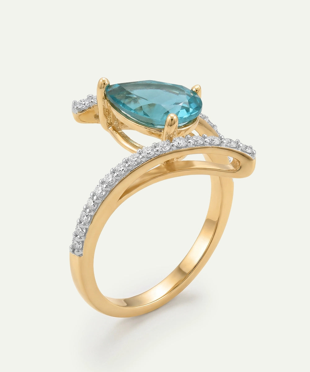 Gold ring with a pear-shaped blue gemstone on a white background