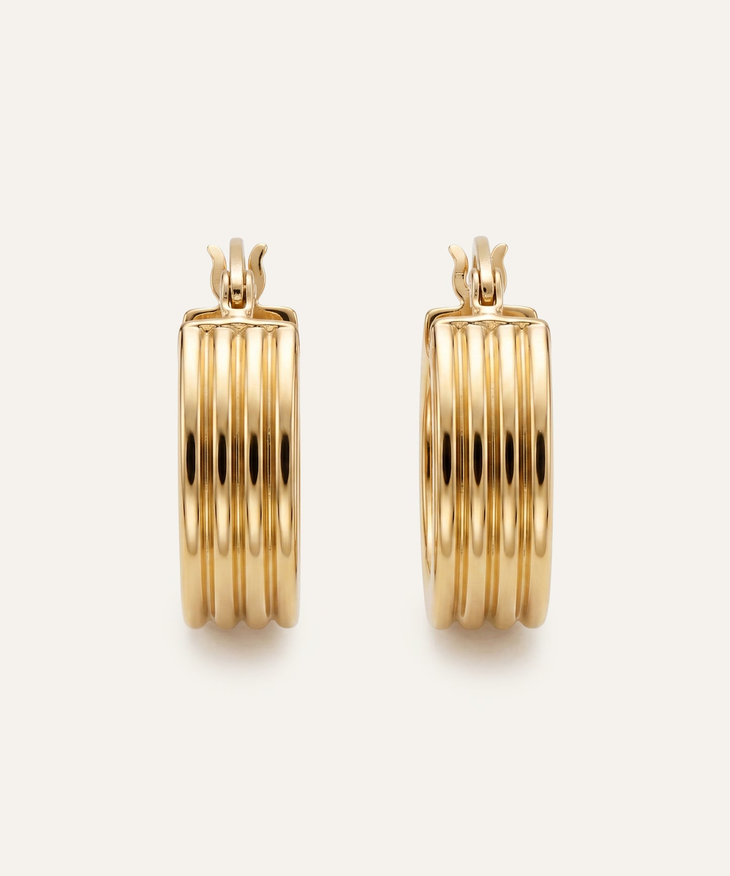 Gold hoop earrings on a light beige background