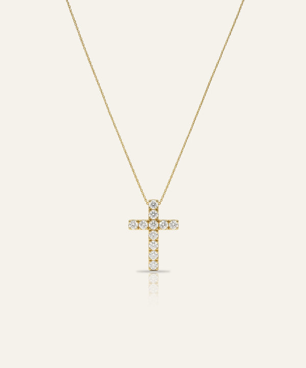 Gold cross necklace with diamonds on a light beige background
