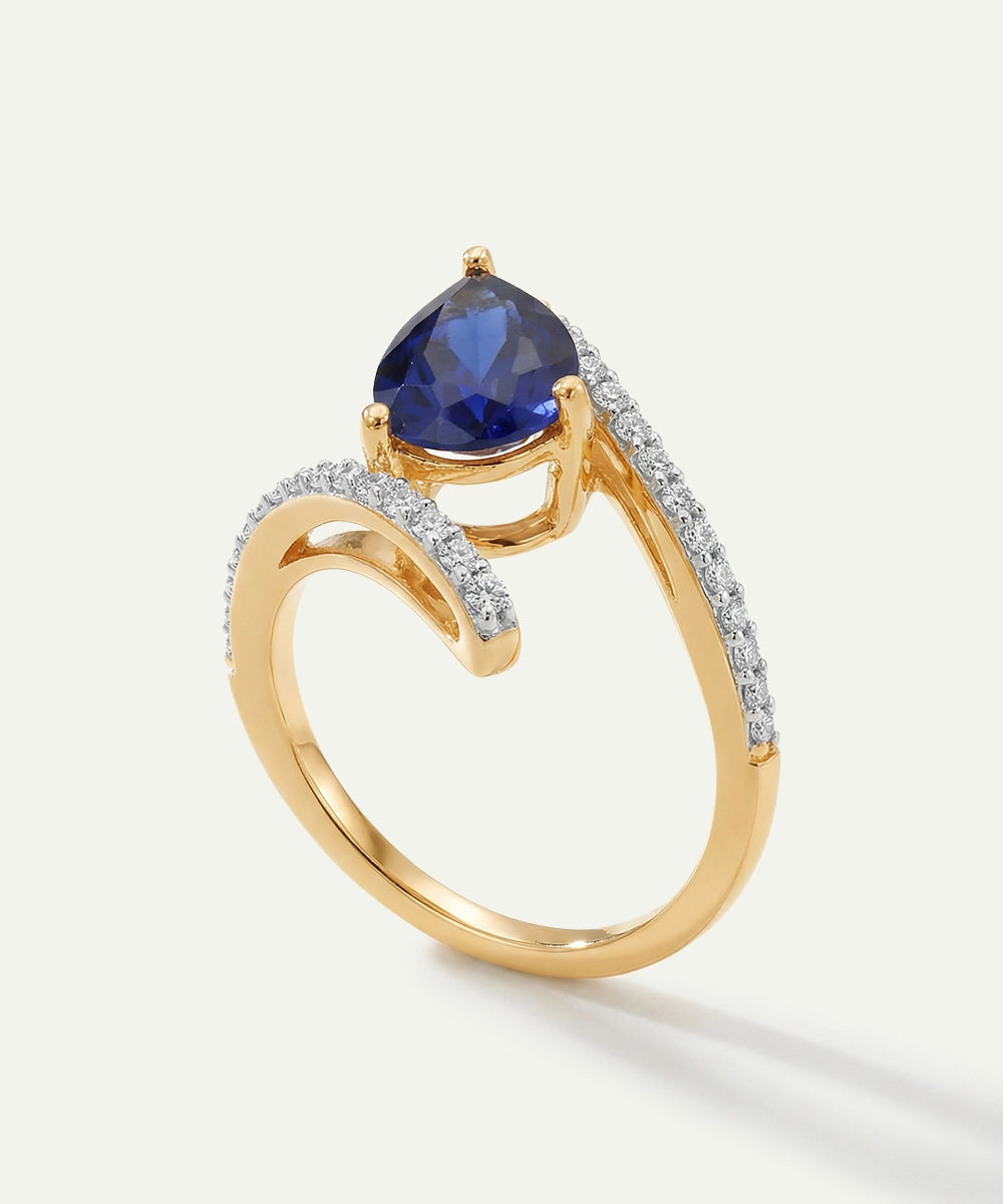 Gold ring with a blue gemstone and diamond accents on a white background