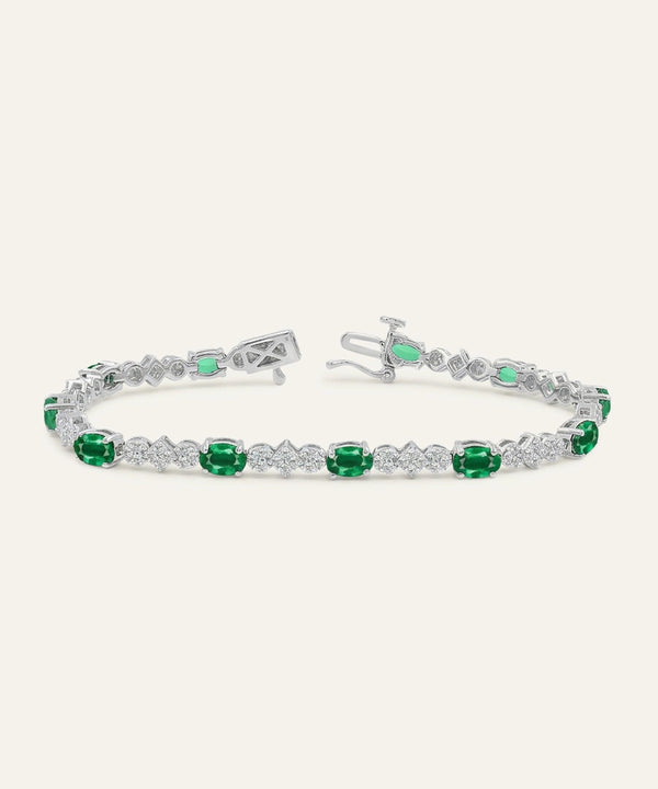 Silver bracelet with green gemstones on a white background