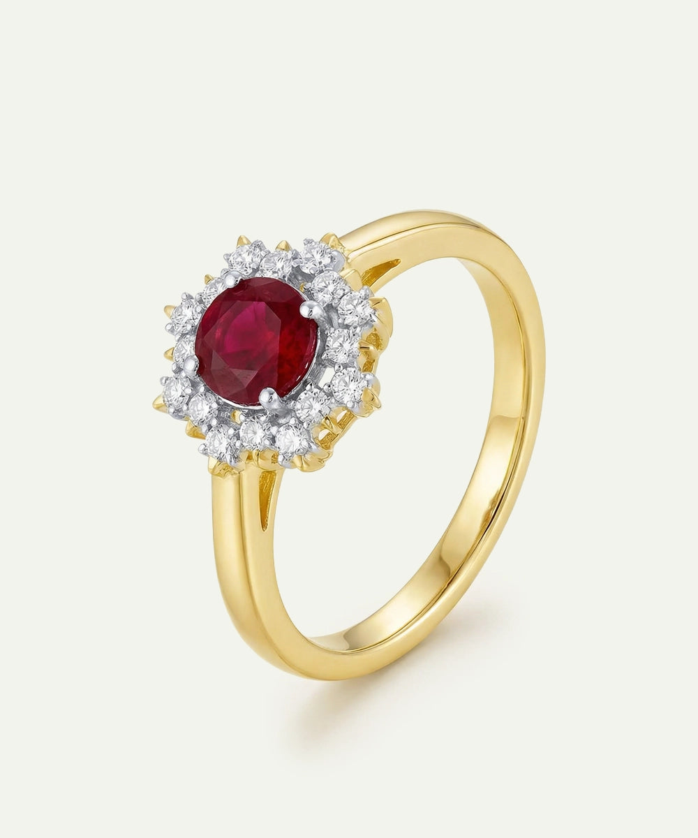 Gold ring with a red gemstone and diamond accents on a light background