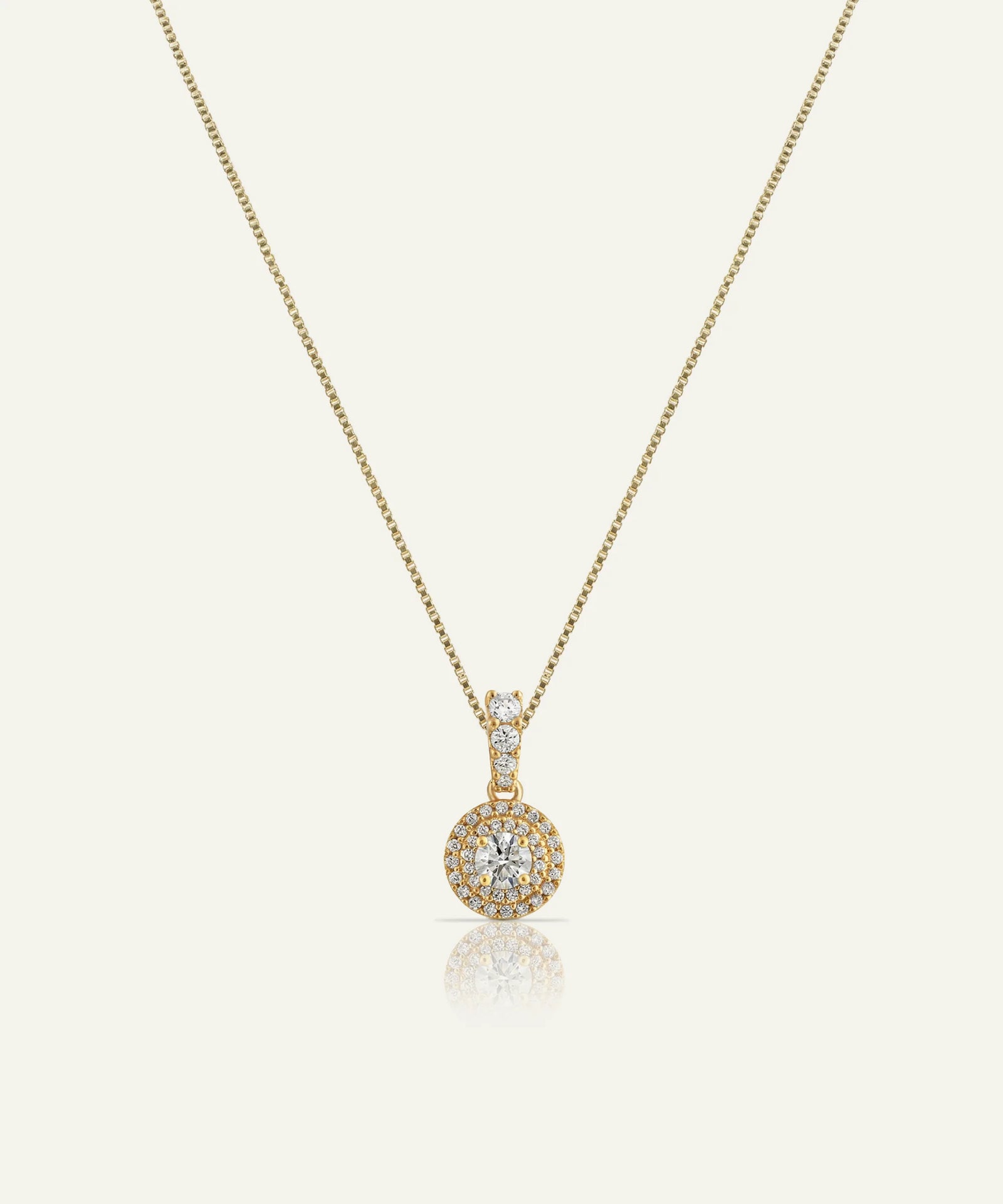 Gold necklace with a round pendant on a white background