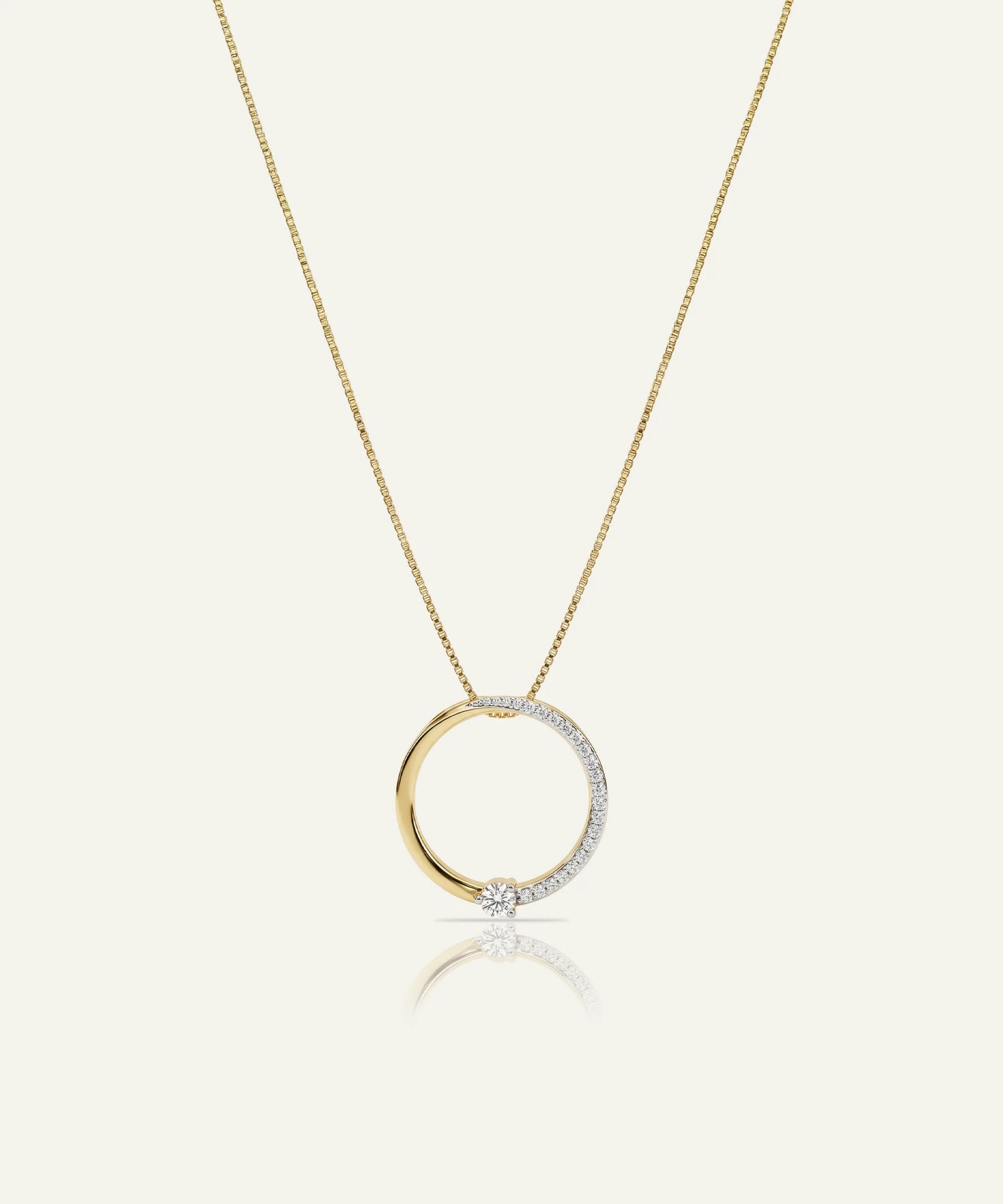 Gold necklace with a circular pendant on a white background