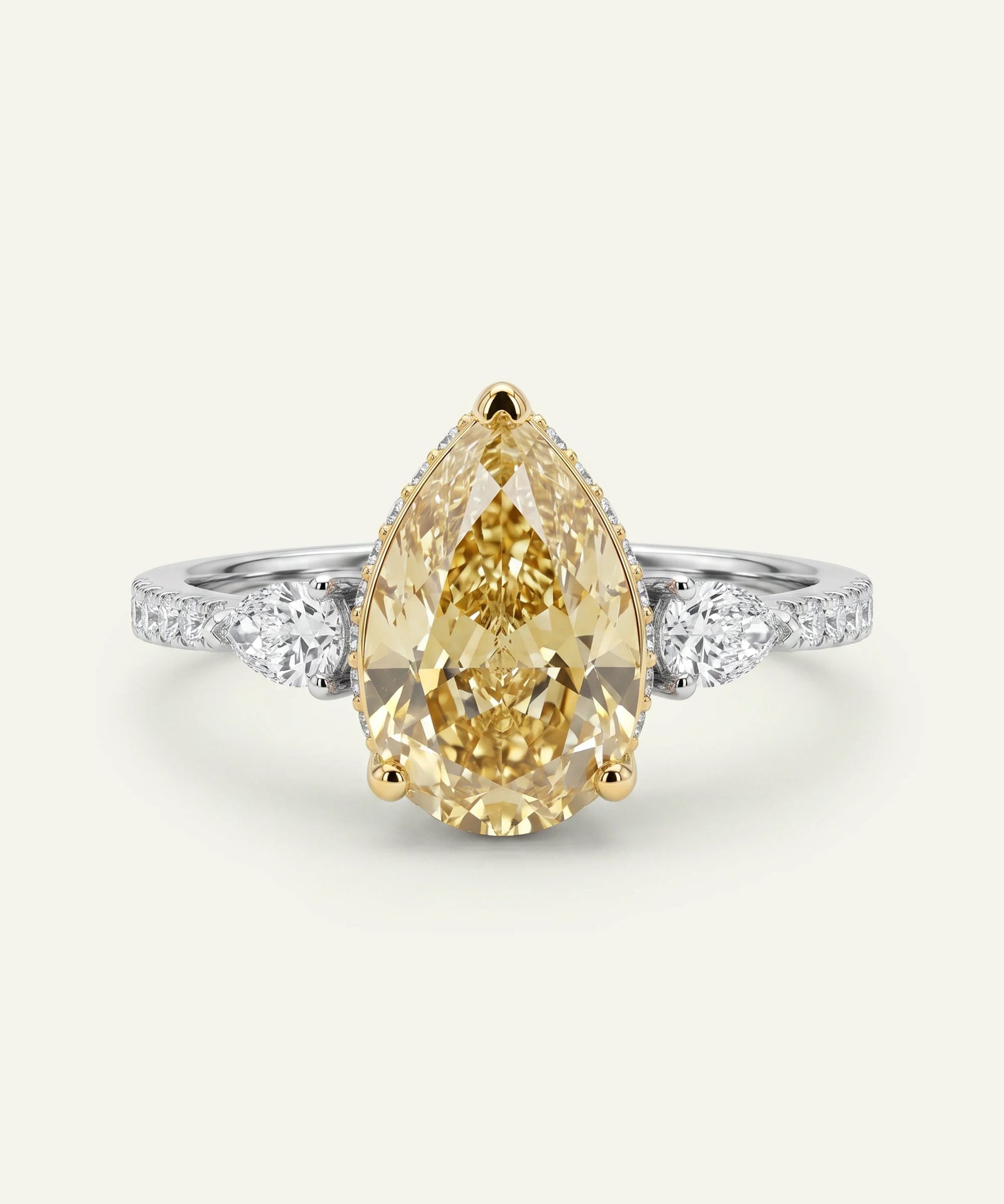 Ring with a pear-shaped yellow diamond and white gemstones on a light gray background