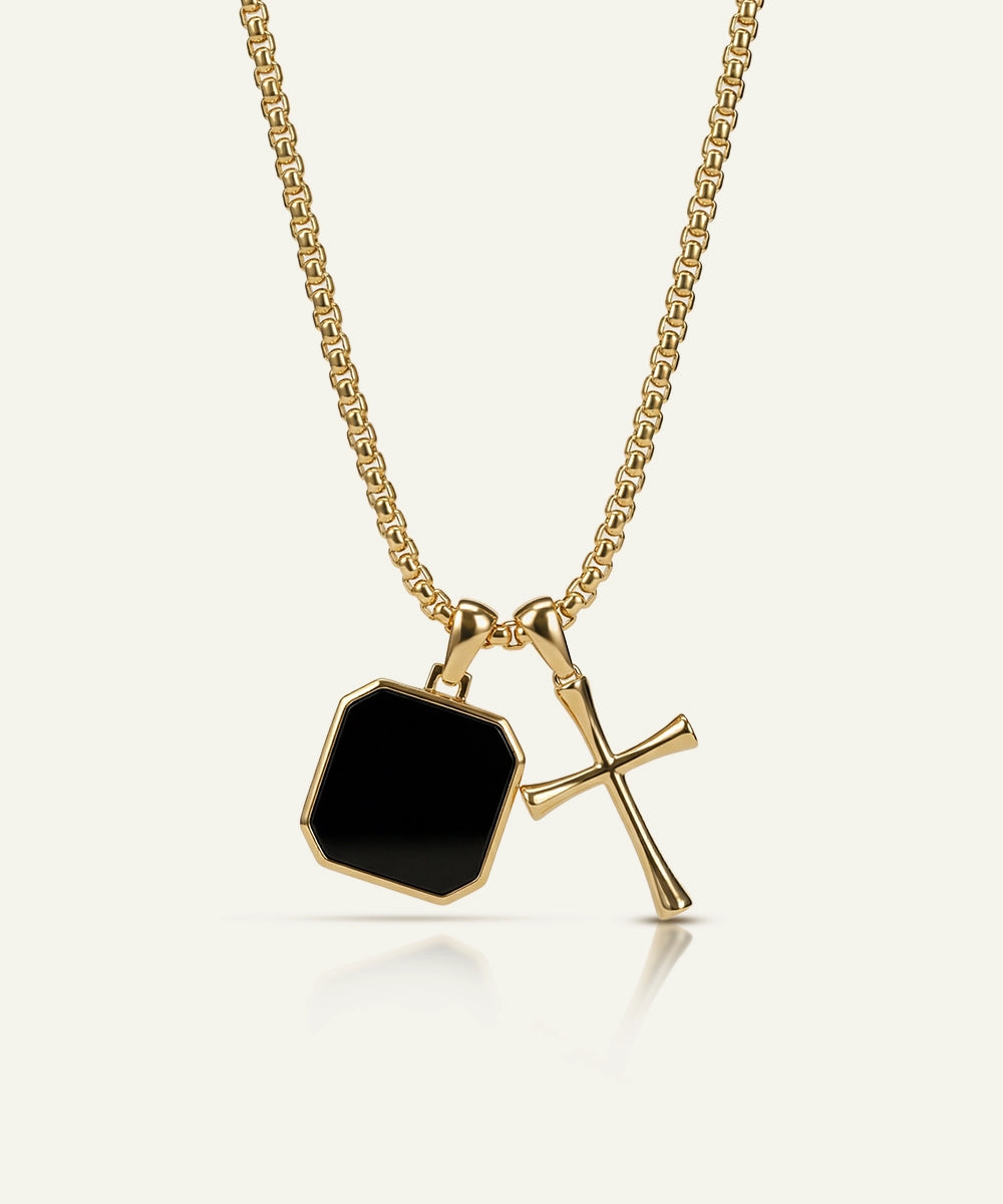 Gold necklace with a black pendant on a white background