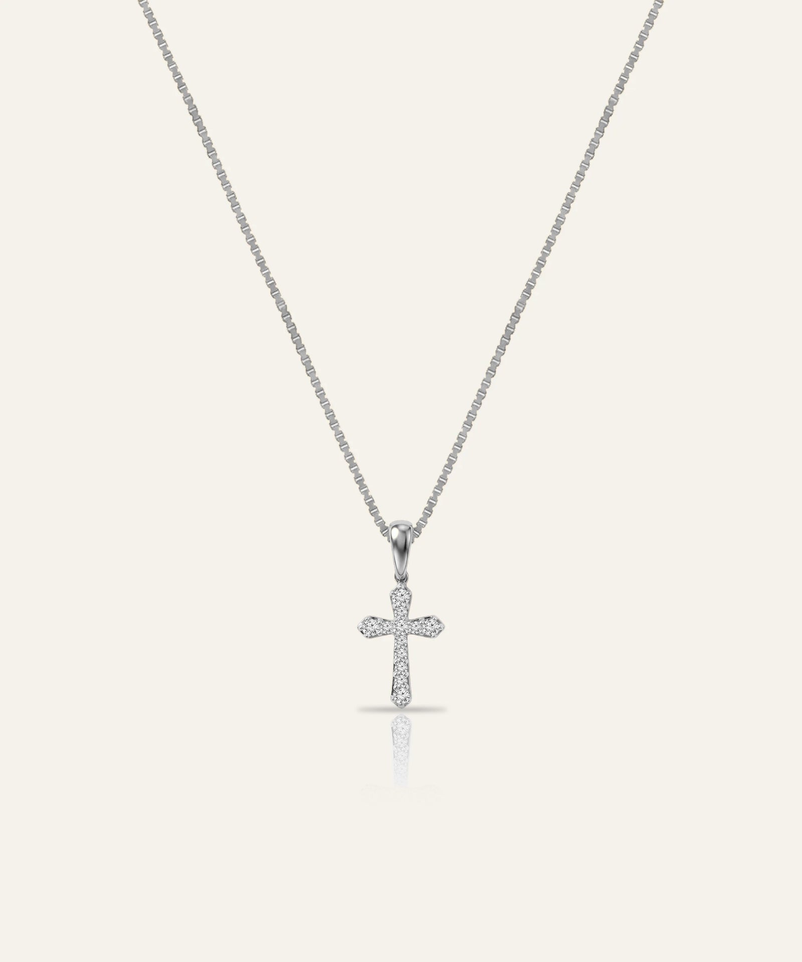 Silver cross pendant necklace on a light gray background