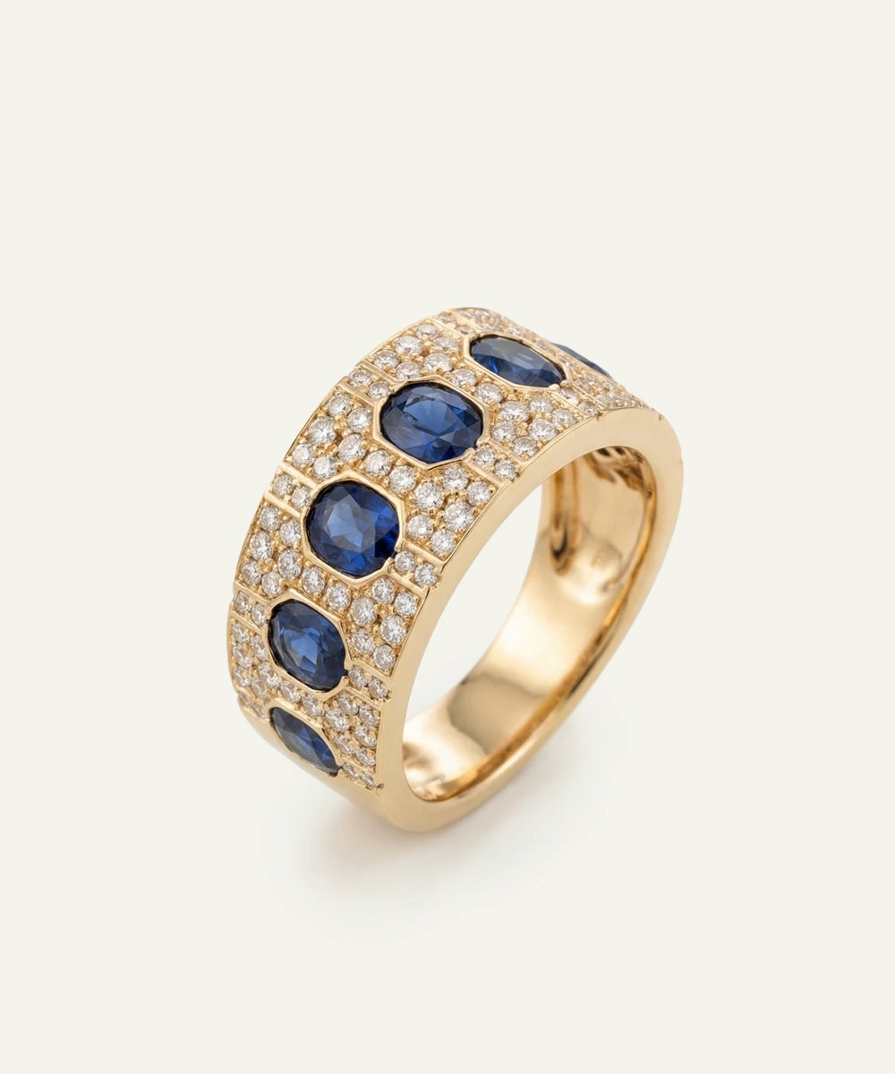 Gold ring with blue gemstones and clear stones on a white background