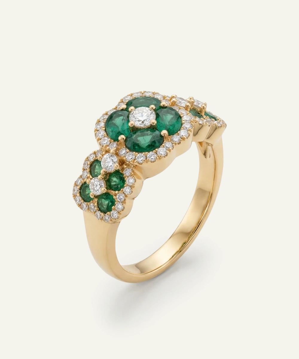 Gold ring with emerald and diamond stones on a white background