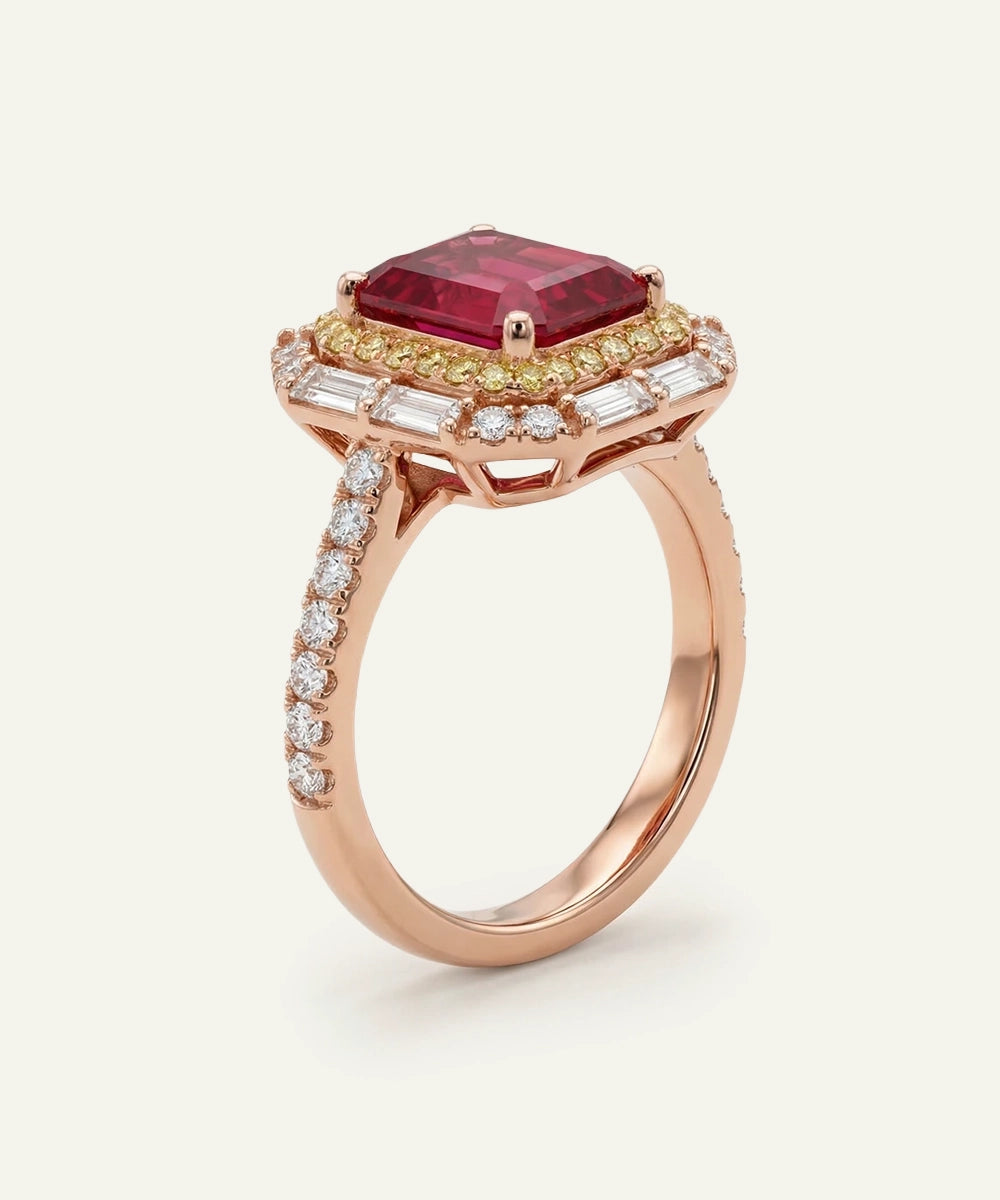 Rose gold ring with a red gemstone and diamond accents on a white background