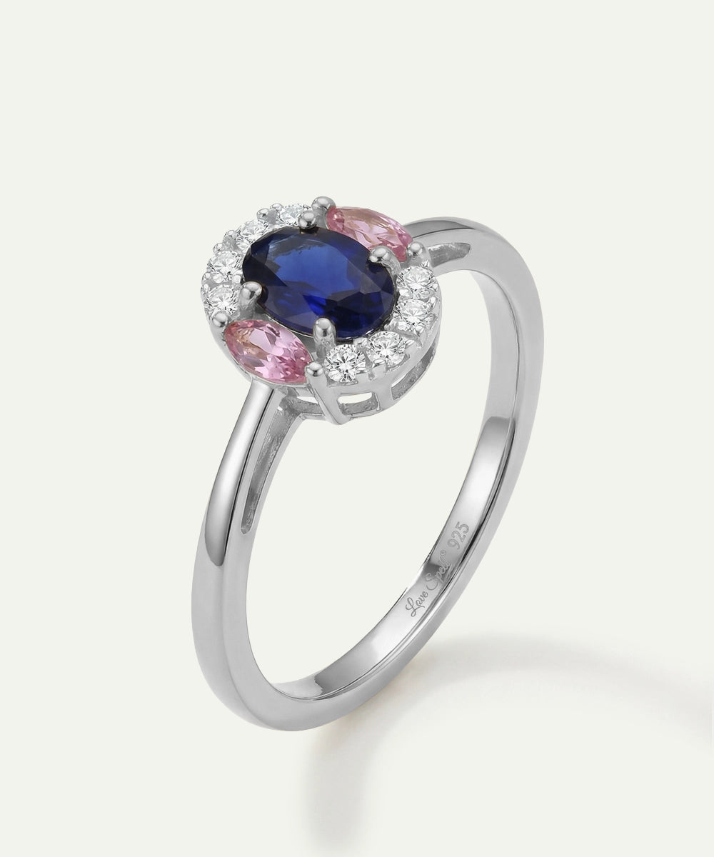 Silver ring with a blue gemstone and pink accents on a white background