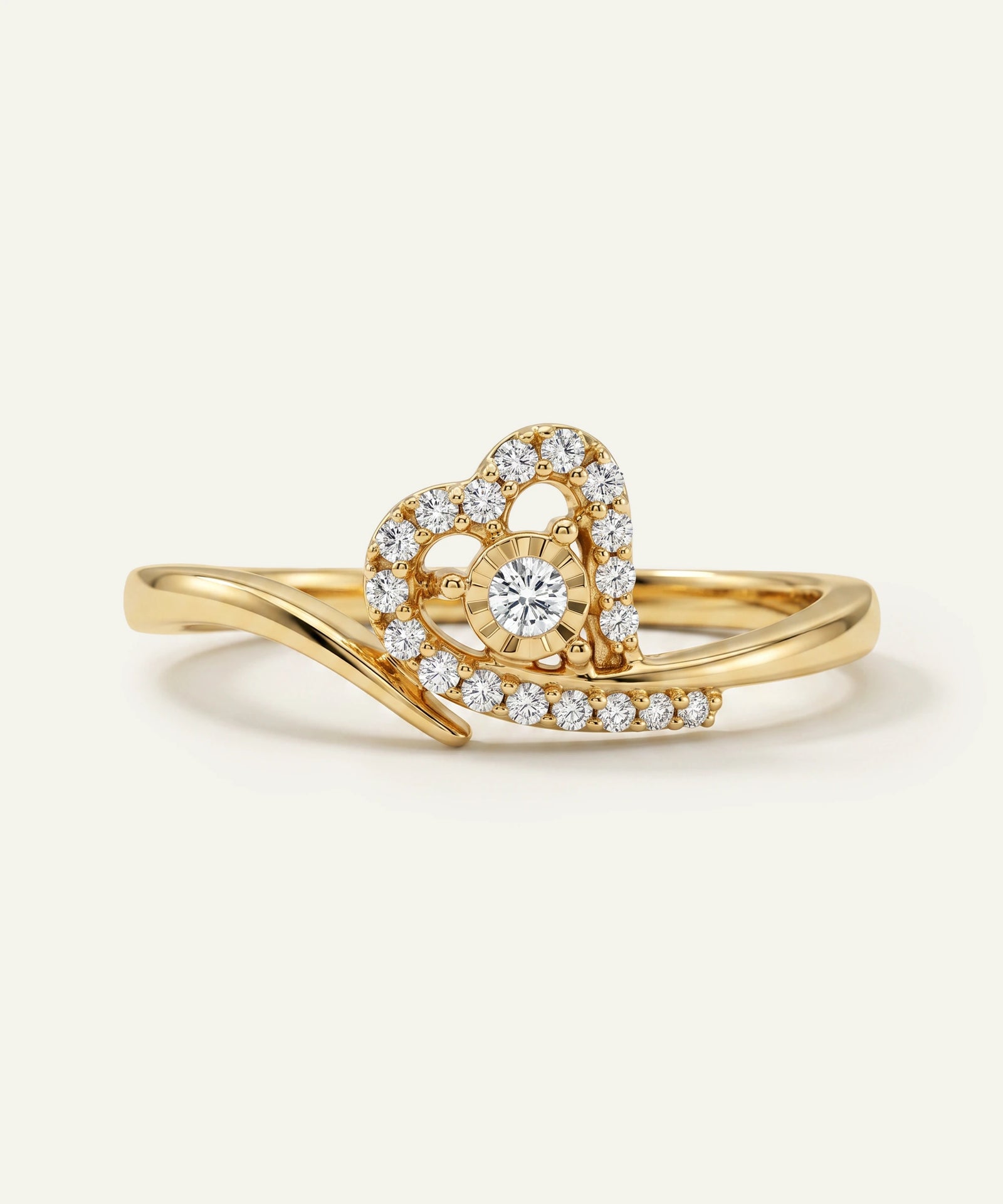 Gold ring with heart-shaped diamond design on a light beige background