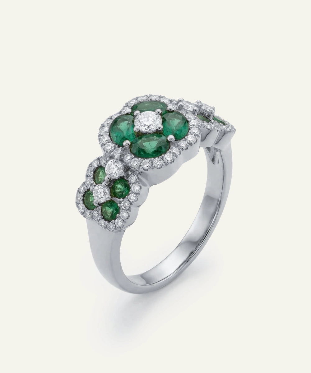 Silver ring with green gemstones on a white background