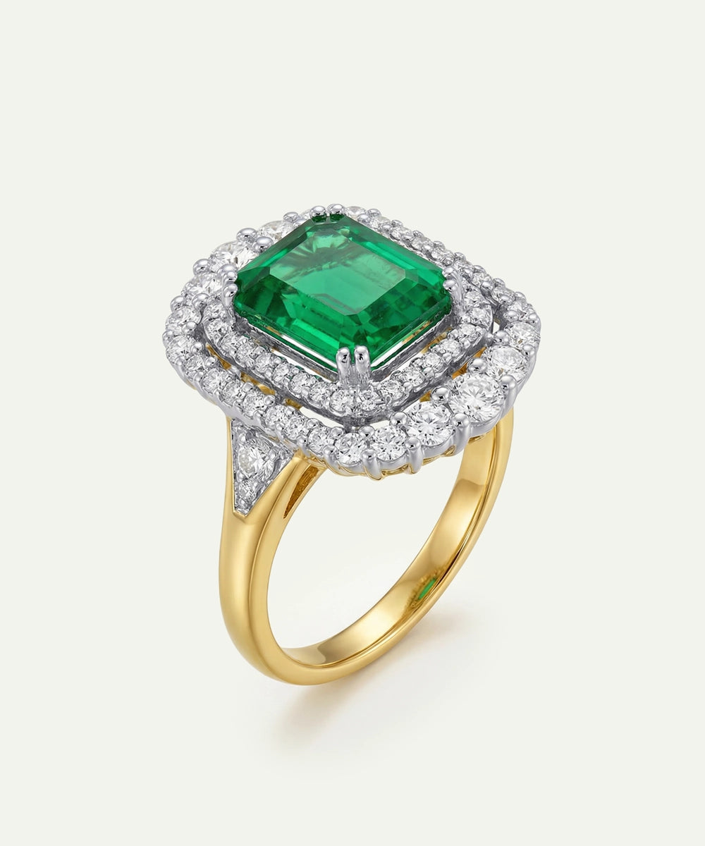 Gold ring with a green gemstone and diamond accents on a white background
