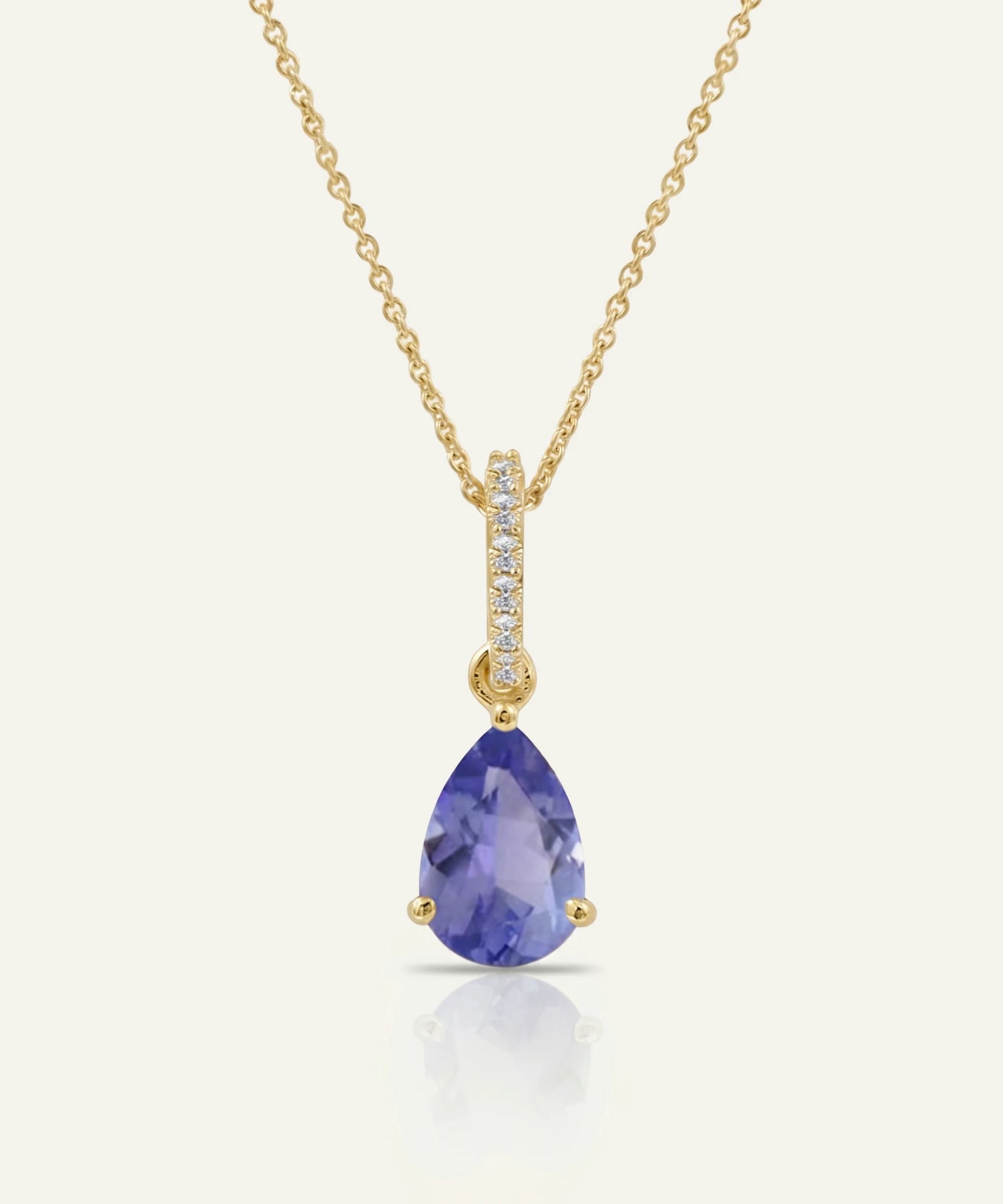 Gold necklace with a purple teardrop pendant on a white background