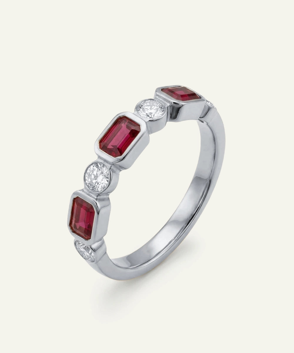 Silver ring with red gemstones and clear stones on a white background