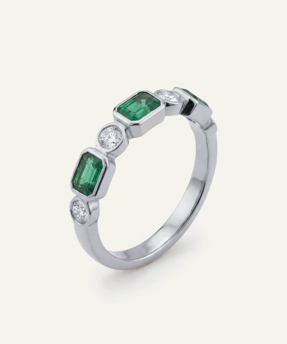 Silver ring with emerald and diamond stones on a white background