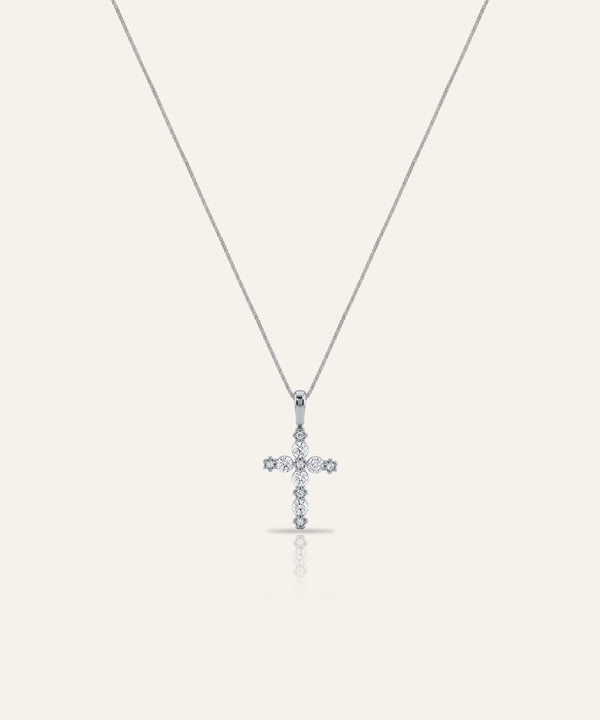 Diamond cross pendant on a thin chain against a light gray background