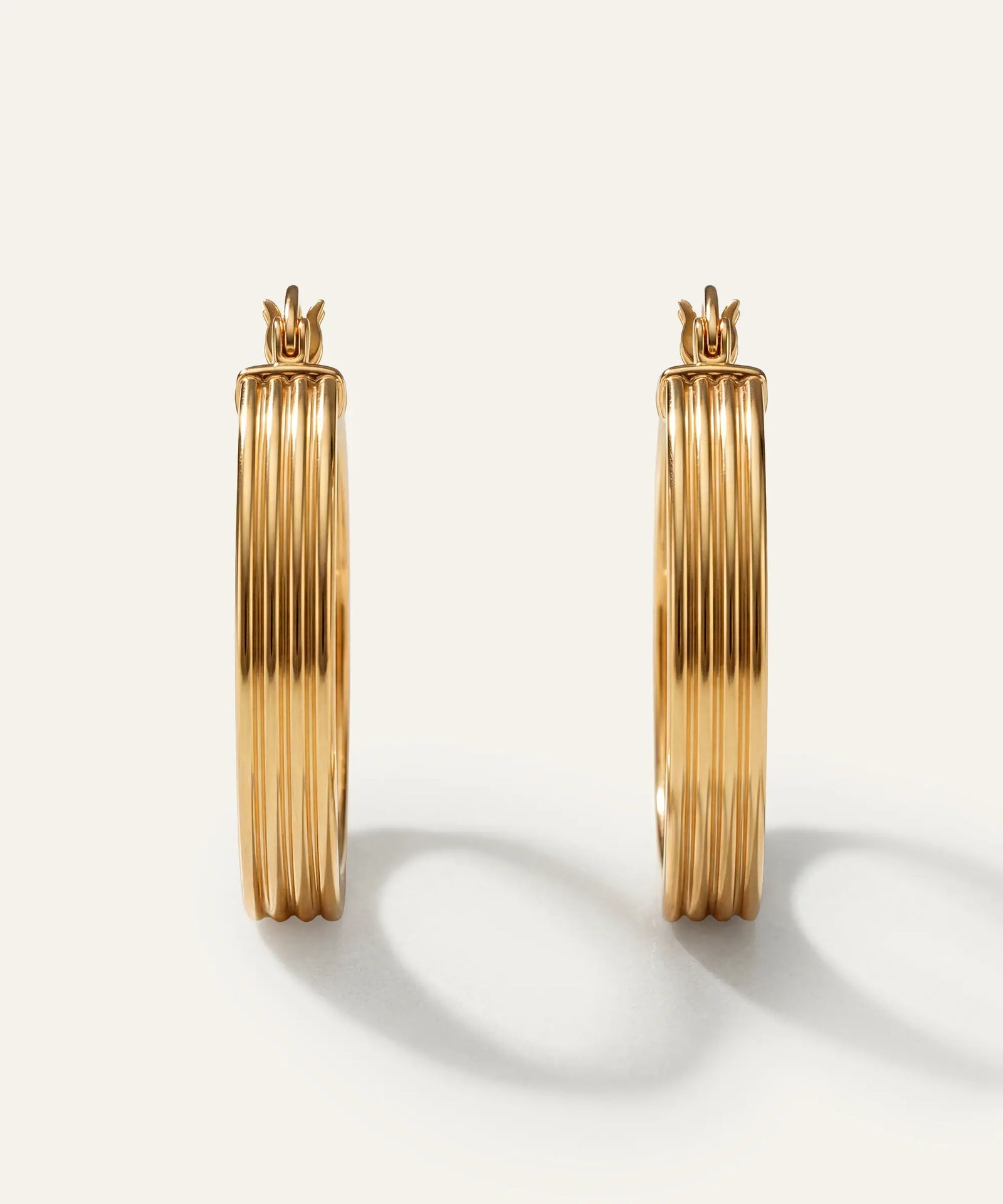 Gold hoop earrings on a light beige background