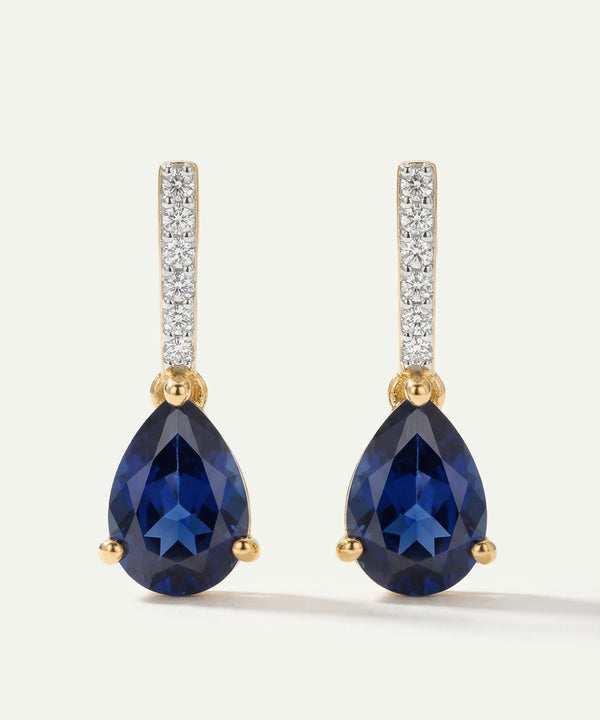 Pair of blue teardrop earrings with gold and diamond accents on a white background