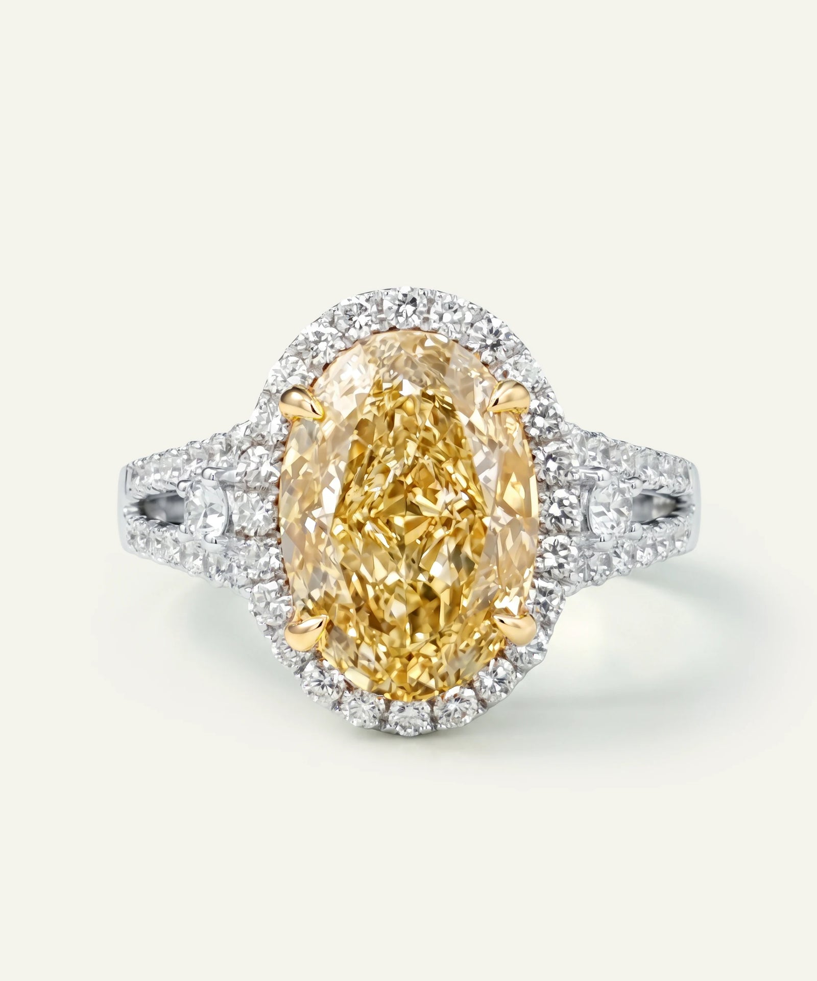 Ring with a yellow diamond and white diamond halo on a light gray background