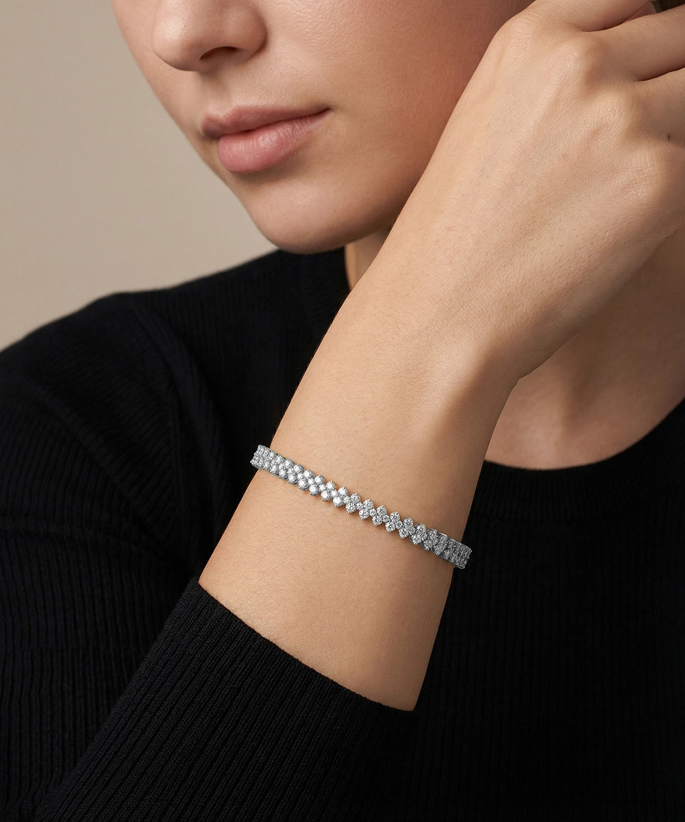 Close-up of a person wearing a silver bracelet on a neutral background