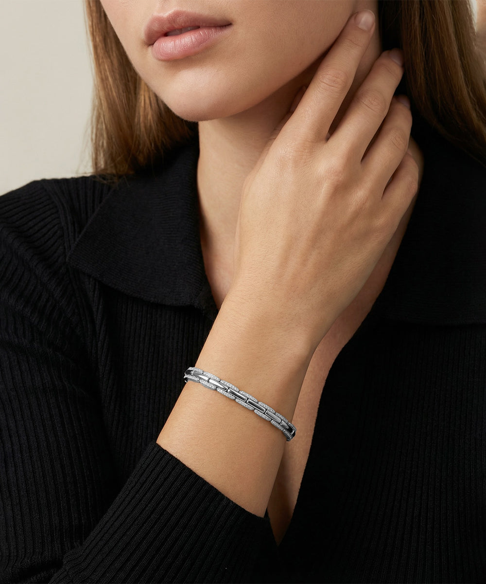 Silver bracelet on a person's wrist with a neutral background