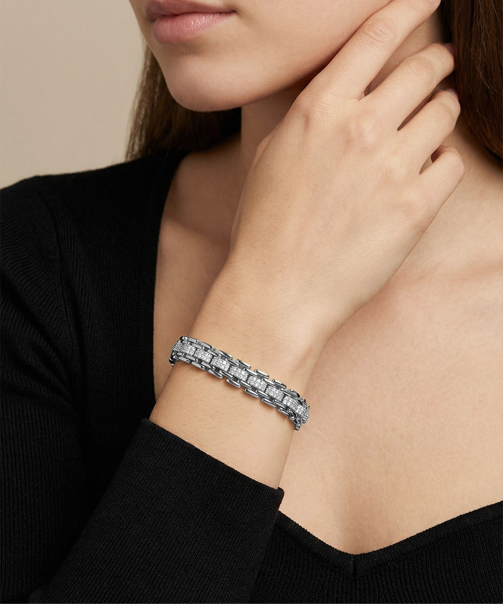 Close-up of a person wearing a diamond bracelet on a neutral background