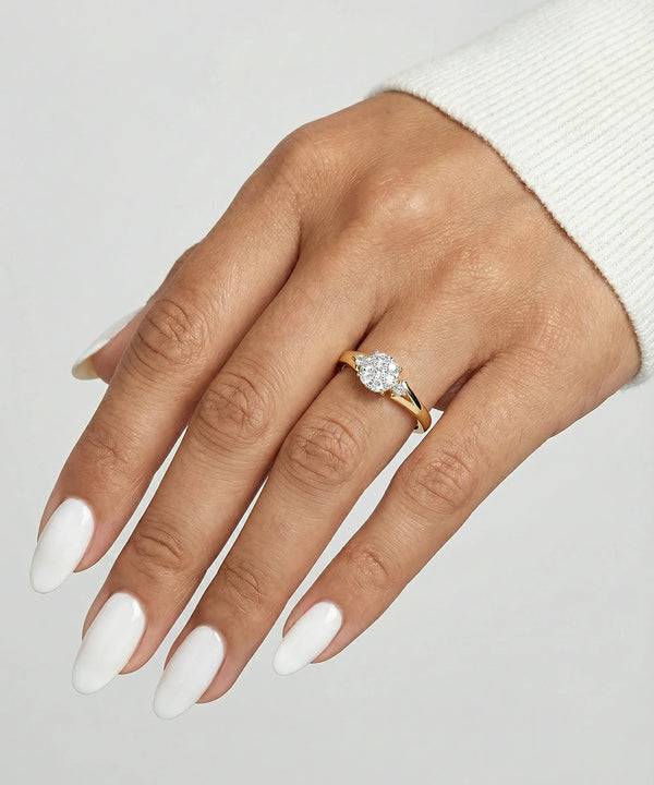 Hand wearing a gold ring with a diamond on a light gray background