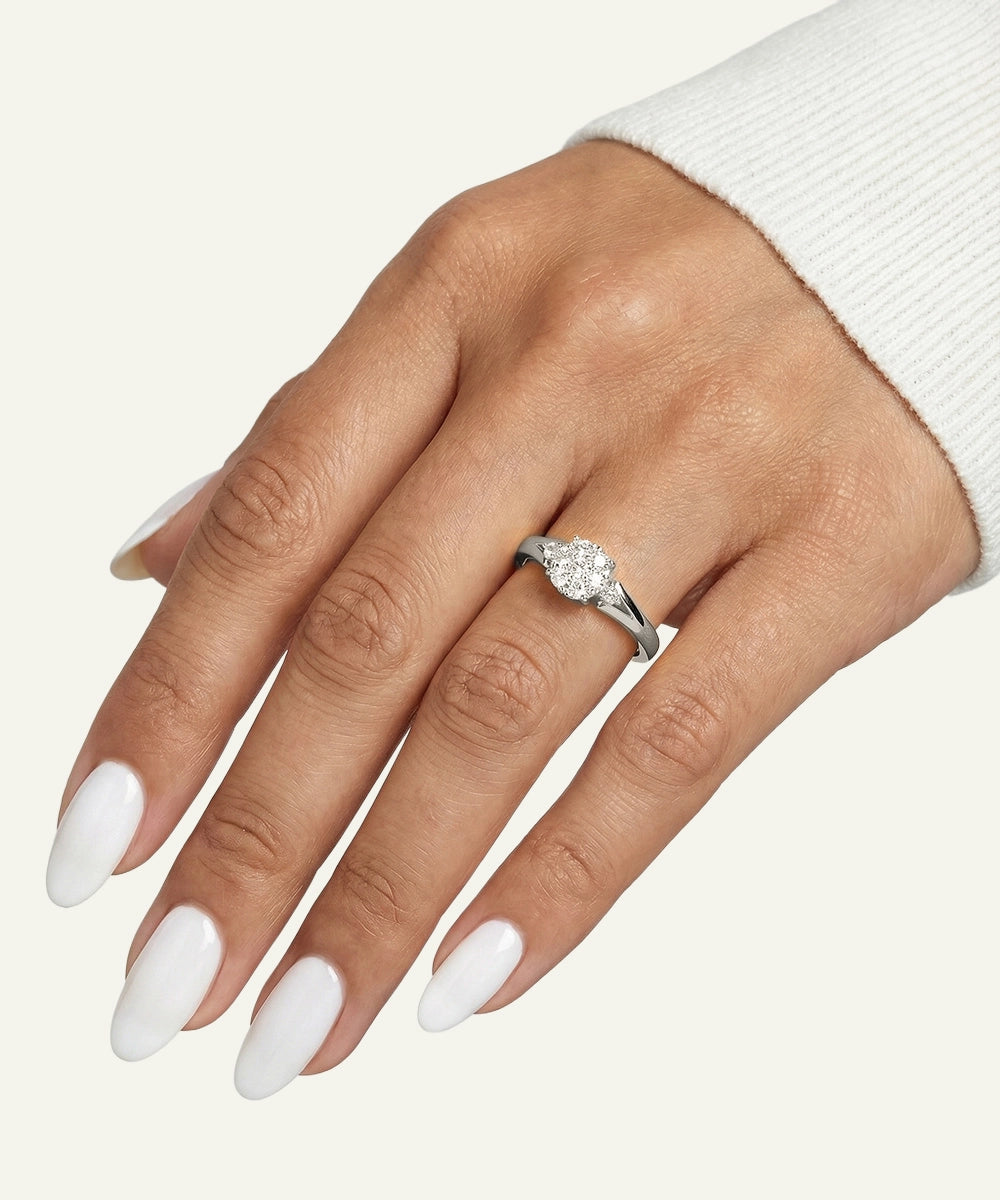 Hand wearing a silver ring with a diamond on a white background