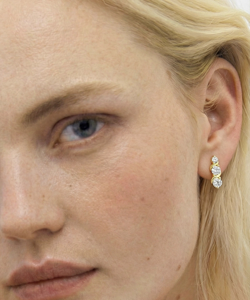 Close-up of a woman wearing gold earrings with clear stones.