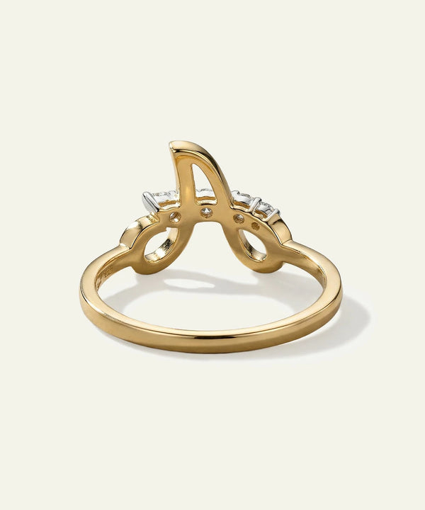 Gold ring with letter 'A' and small diamonds on a light gray background