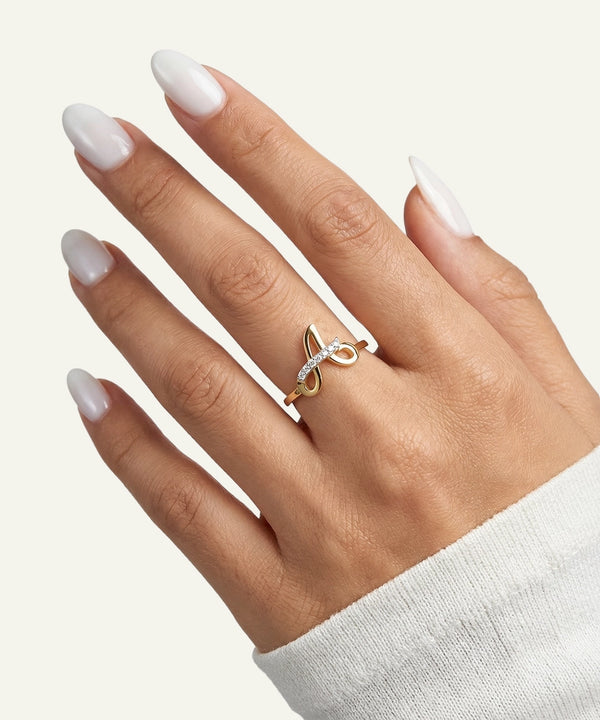 Hand wearing a gold ring with small diamonds on a neutral background