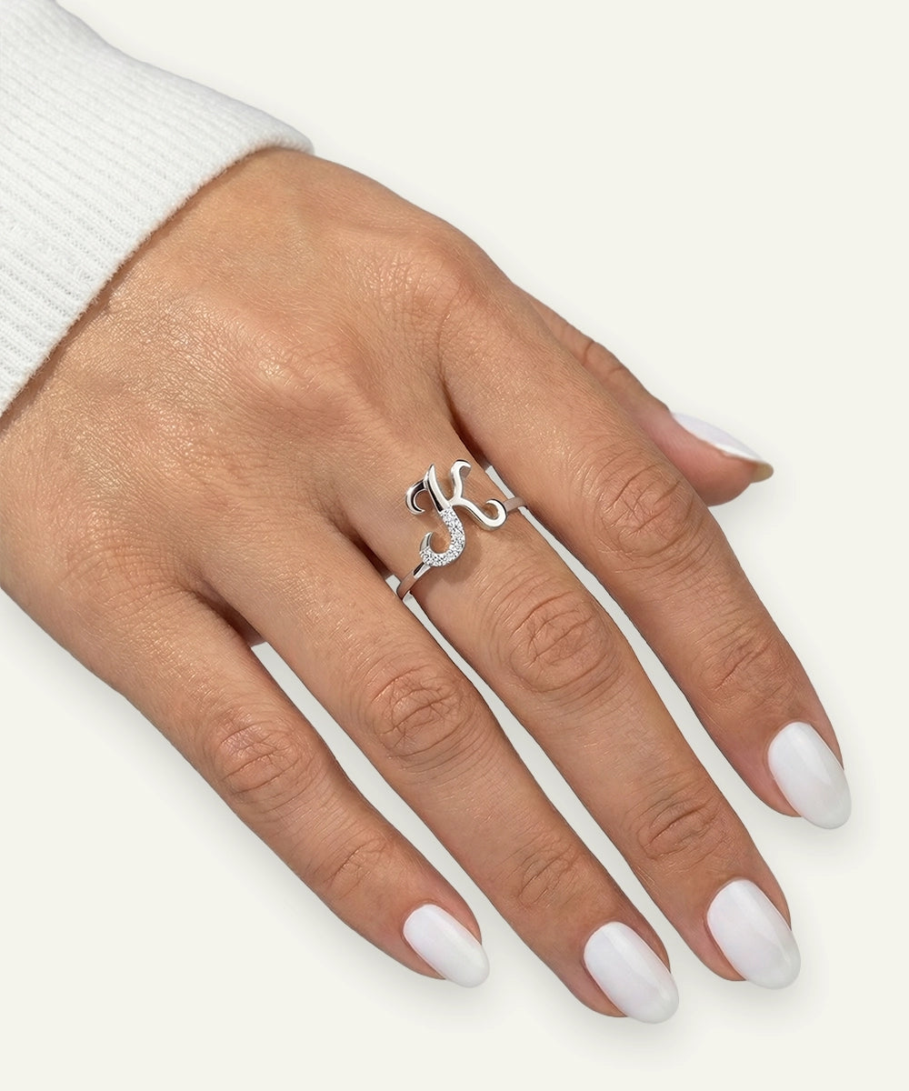 Hand wearing a silver ring with a decorative design on a white background