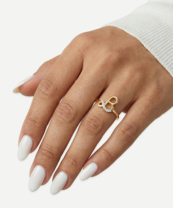 Hand wearing a gold ring with a heart and key design on a white background