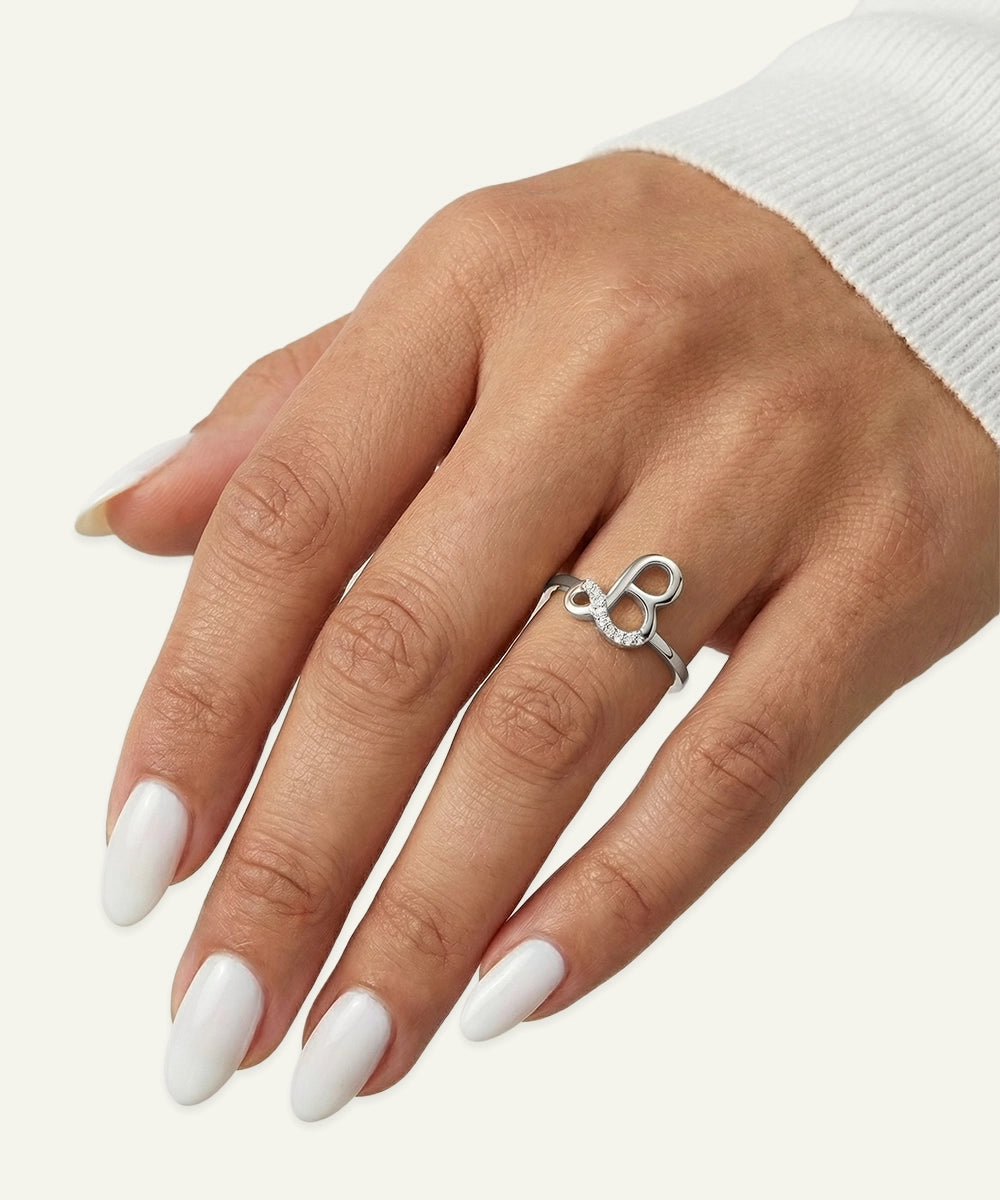 Hand wearing a silver ring with a unique design on a white background