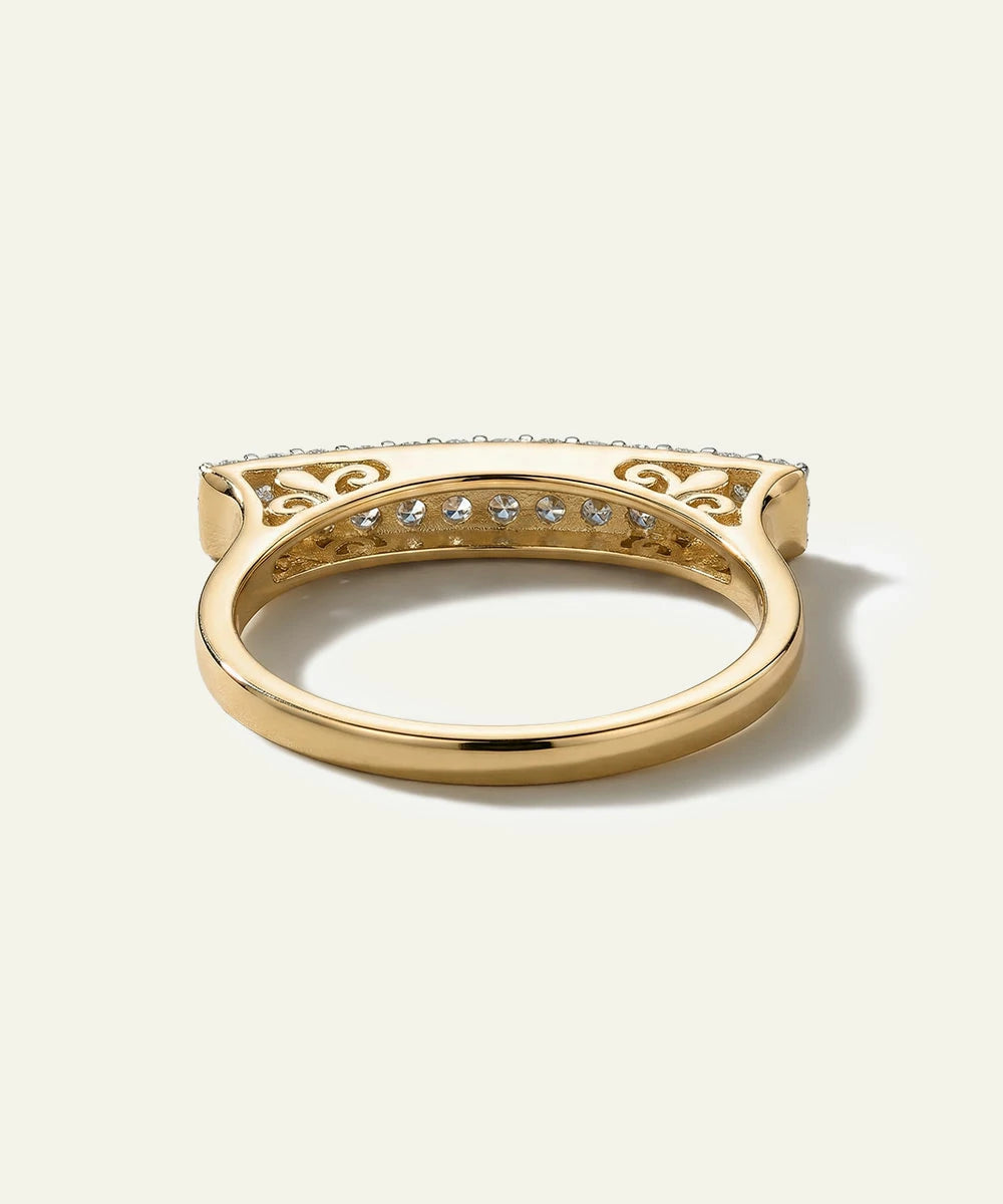 Gold ring with diamond accents on a light beige background
