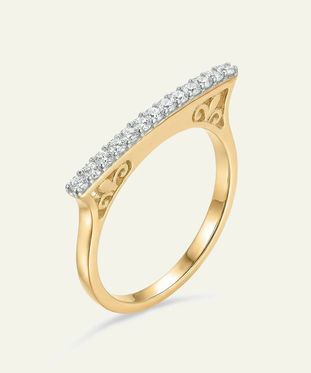 Gold ring with diamond accents on a light beige background