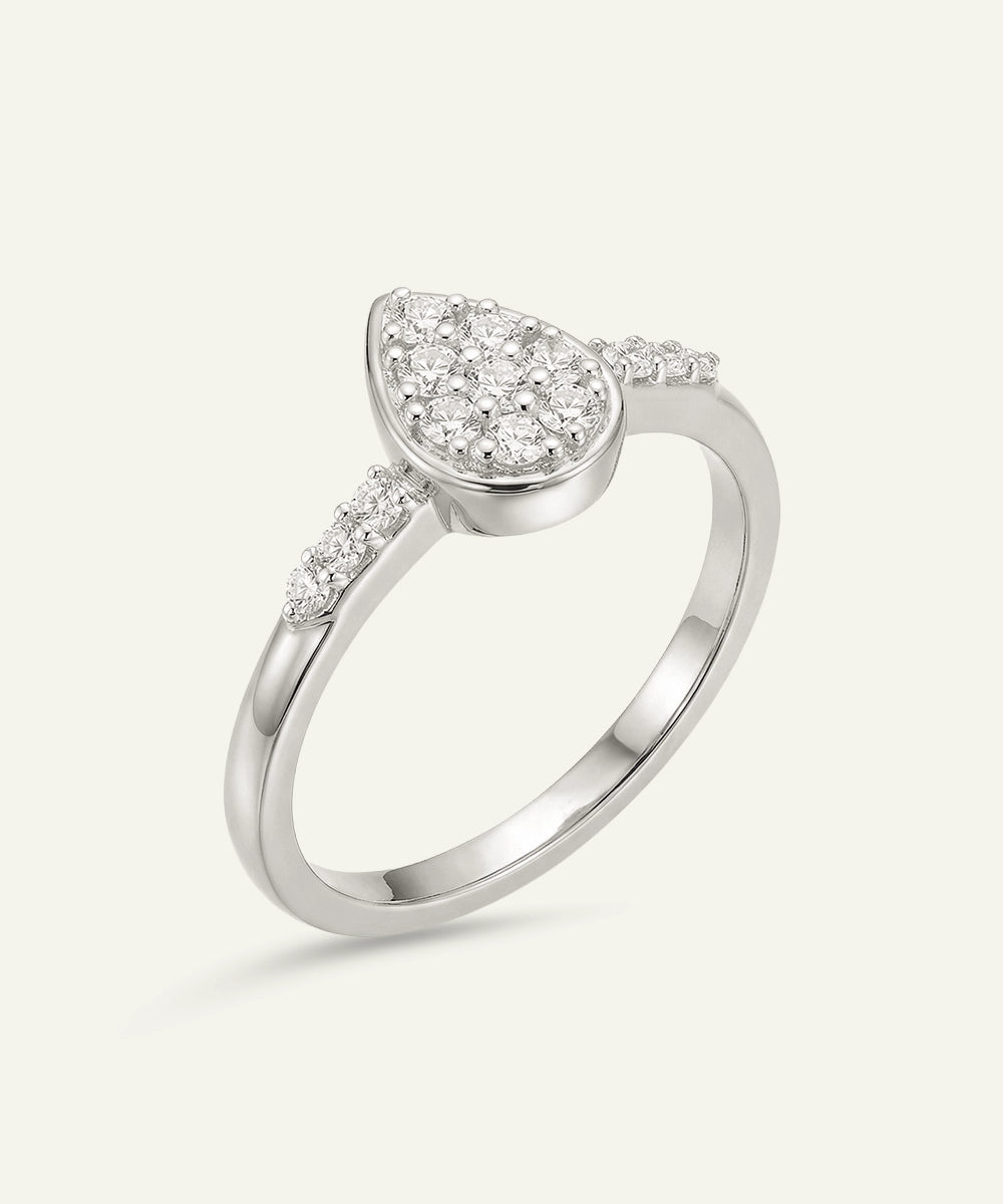 Silver ring with a pear-shaped diamond center on a white background