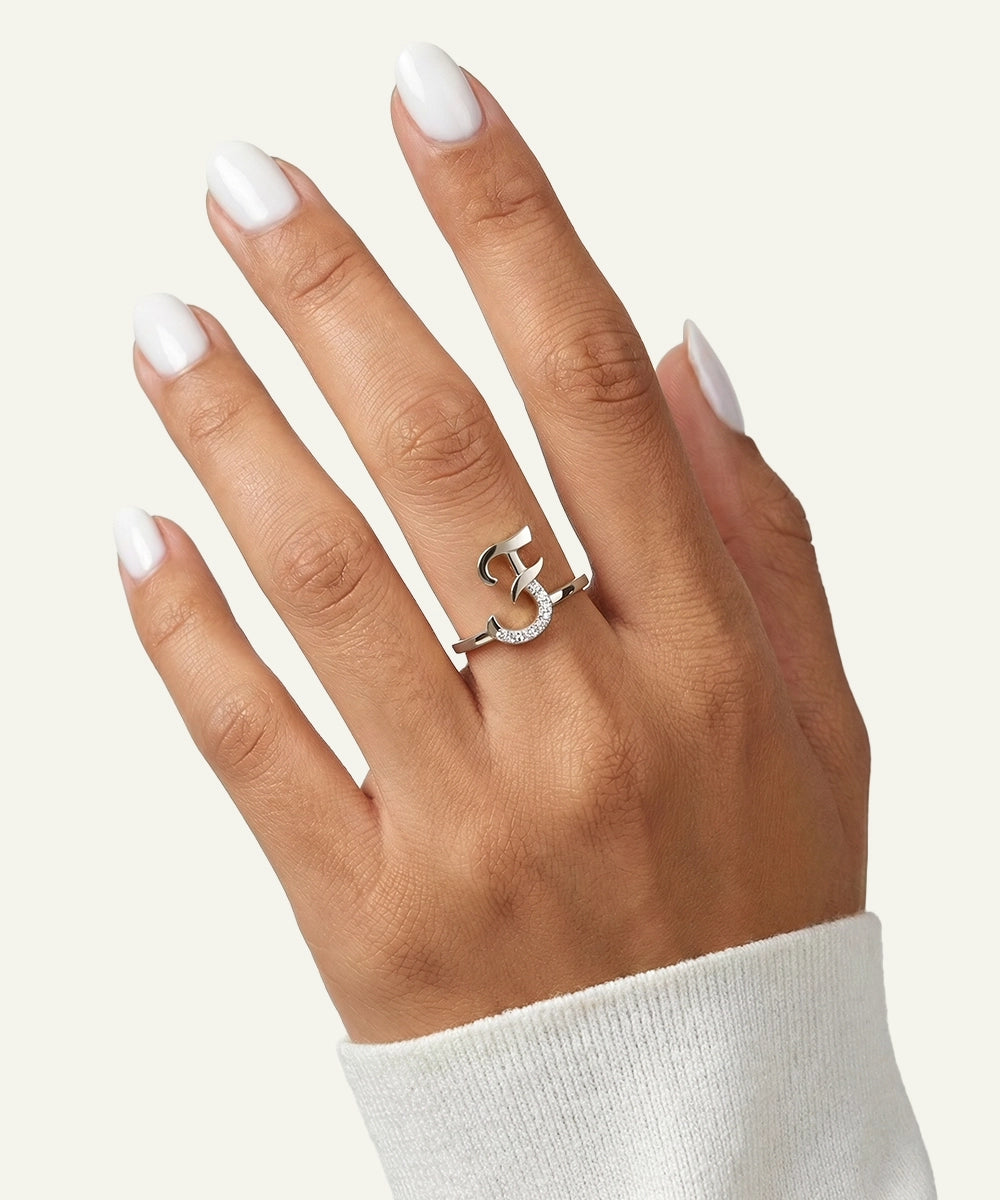 Hand wearing a silver ring with a heart design on a white background