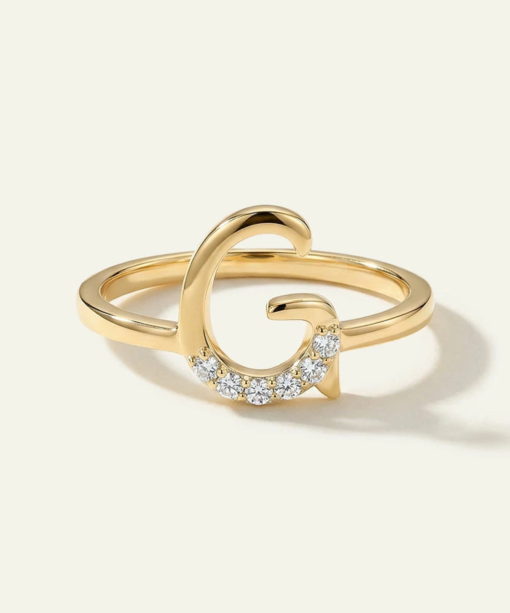 Gold ring with diamond accents on a light beige background