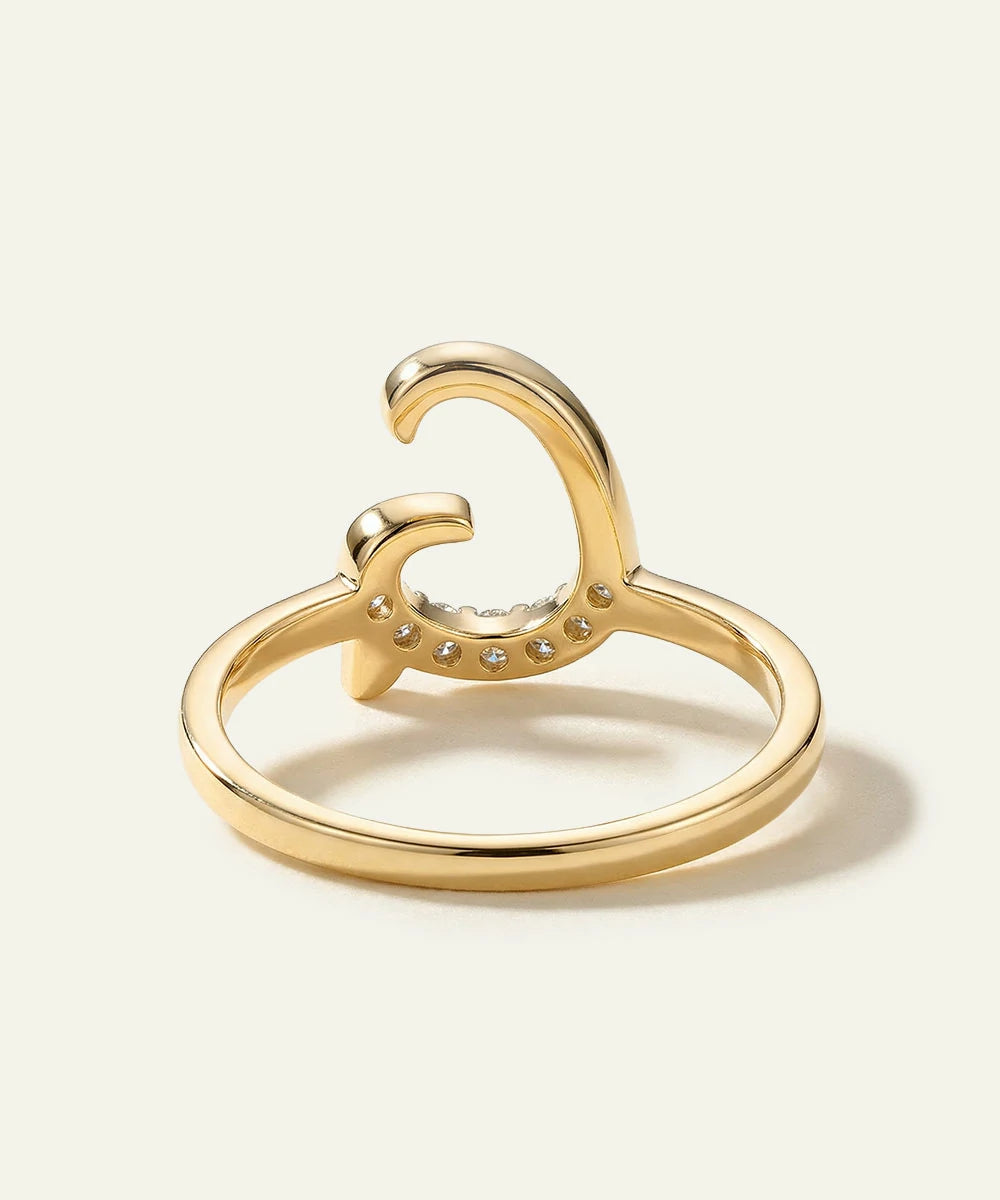 Gold ring with heart and moon design on a light background