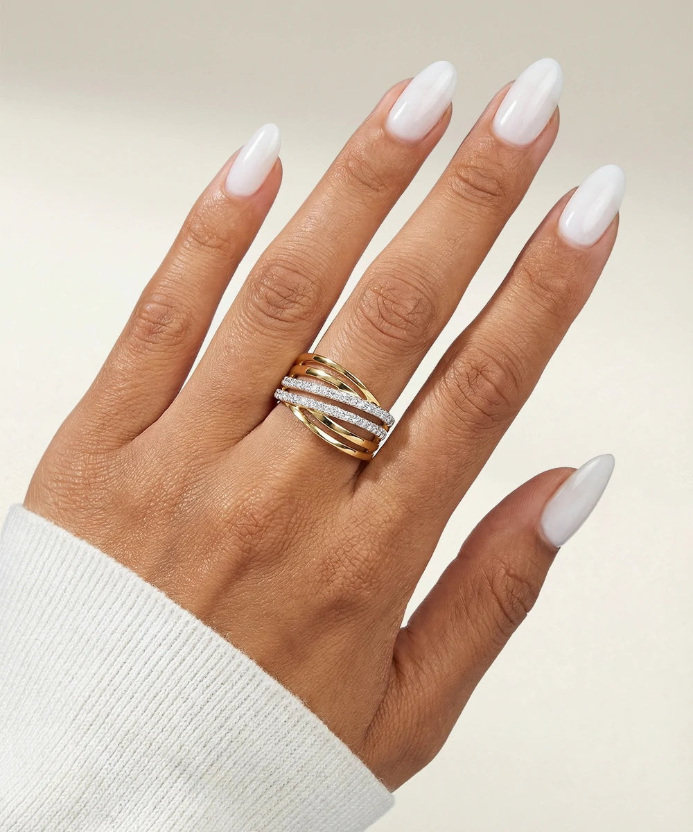 Hand wearing a gold ring with a diamond band on a neutral background
