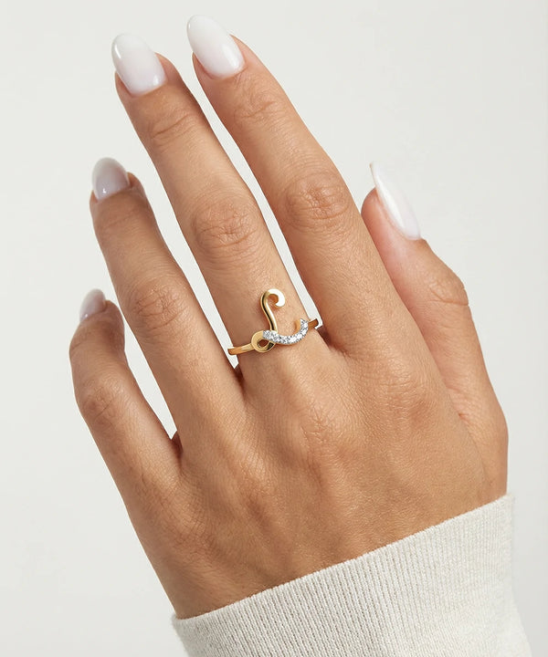 Hand wearing a gold ring with a diamond on a light gray background