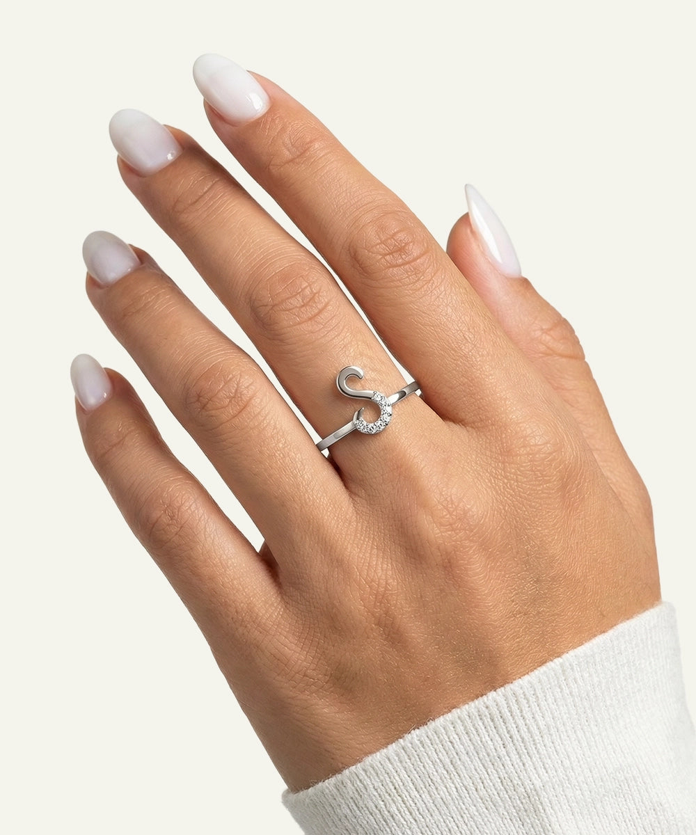 Hand wearing a silver ring with a diamond on a light gray background