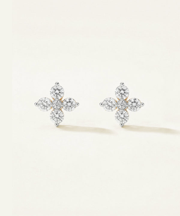 Pair of diamond-cross earrings on a light beige background