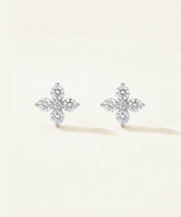 Pair of diamond cross earrings on a light beige background