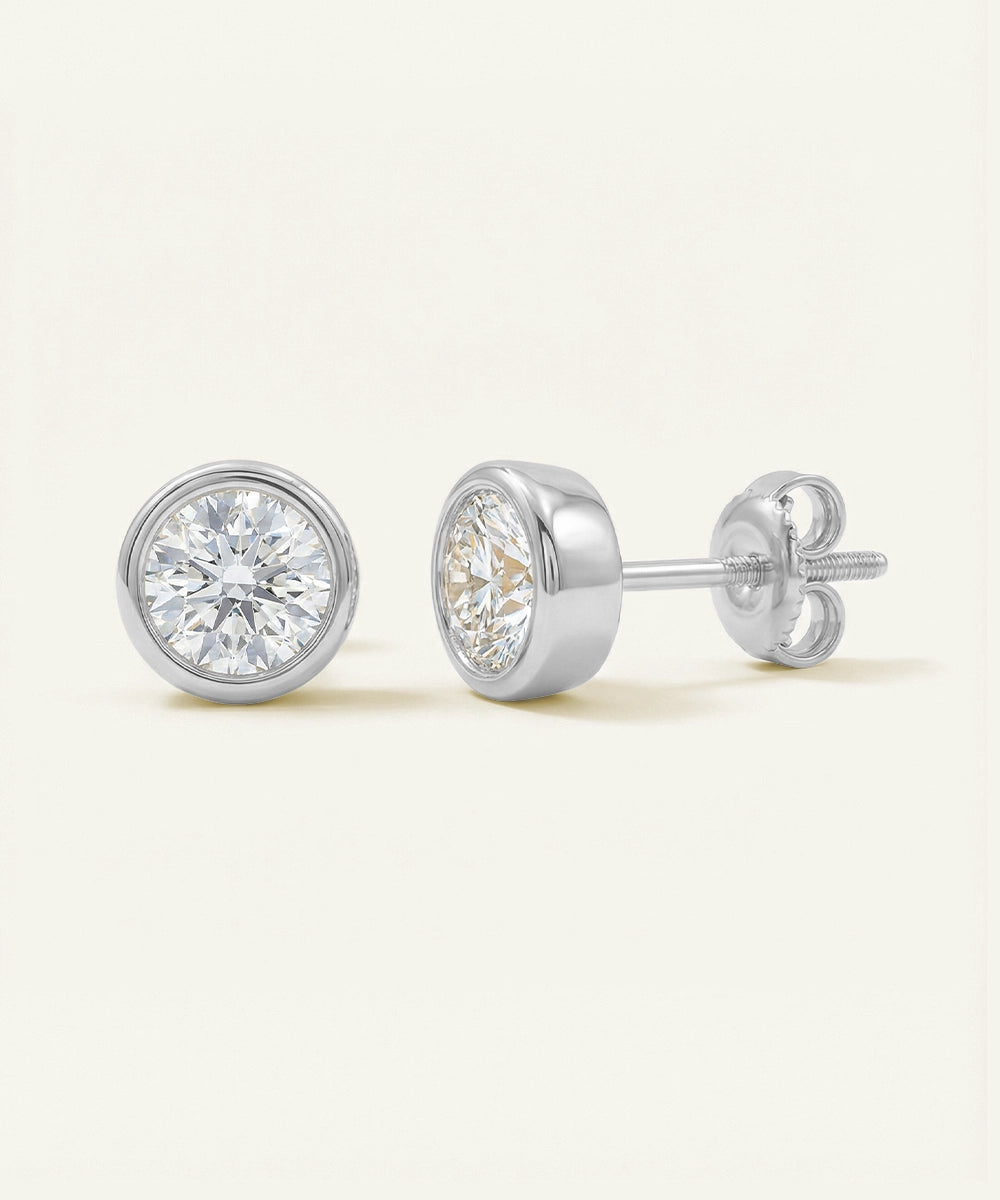 Pair of diamond stud earrings on a light beige background